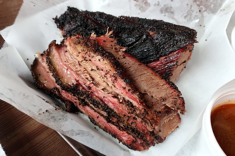 Smoked Central Texas Brisket, sliced, on white platter.