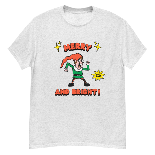 White T shirt with a retro-style elf character with a red hat, green suit, and black boots. The elf is striking a playful pose with a "Stay Good" speech bubble.