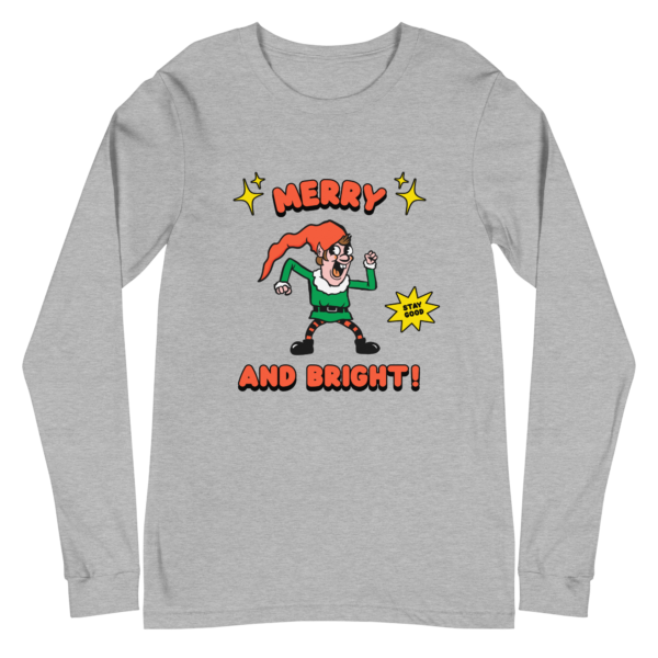 White long sleeved T shirt with a retro-style elf character with a red hat, green suit, and black boots. The elf is striking a playful pose with a "Stay Good" speech bubble.